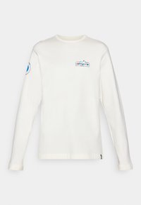 White long-sleeve shirt made of soft cotton, featuring a multicolored Patagonia logo on the chest and a circular logo on the sleeve.