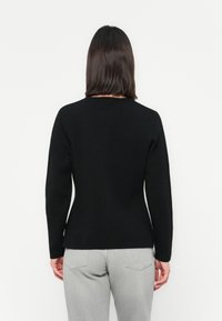 Sort tilpasset genser med rund hals og lange ermer, laget av mykt stoff. Har en glatt tekstur og et elegant bakdesign.