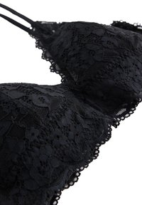 Schwarzer Spitzen-BH mit floralem Muster, dünnen verstellbaren Trägern und gewellten Kanten. Texturiertes Material mit filigranen Details.