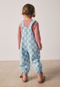 Blå og lyseblå ternede denimoveralls med elastiske manchetter, kombineret med en lyserød langærmet top og blush-ankelstøvler med kvaster.