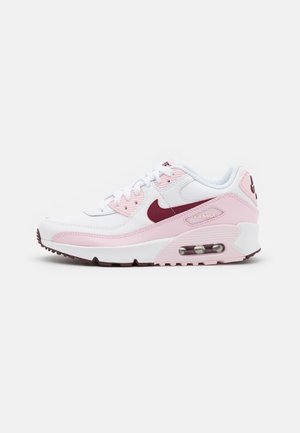 Baskets Nike Air Max blanches et roses avec un swoosh bordeaux et une semelle avec coussin d’air visible sur un fond blanc uni.