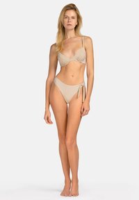 Beżowy zestaw bikini z wyprofilowanym trójkątnym stanikiem z regulowanymi ramiączkami oraz szortami z wysokim stanem i wiązaniem po boku. Gładka faktura.