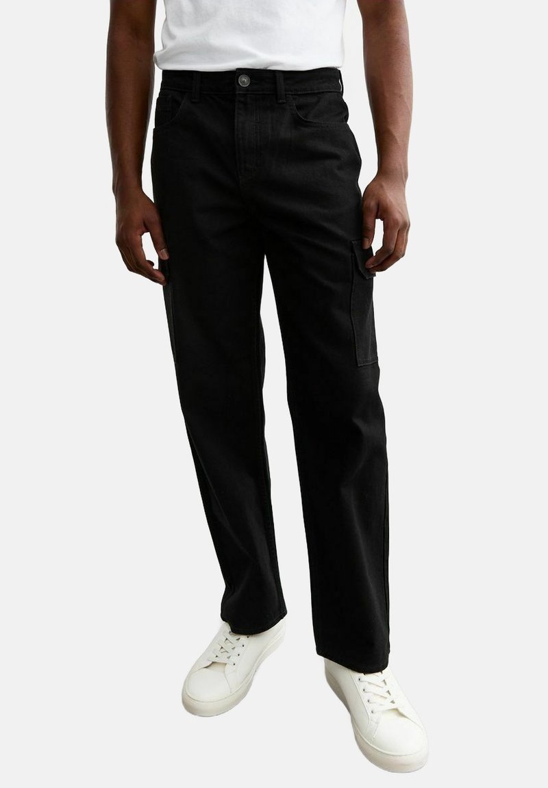 Pantaloni cargo neri realizzati in cotone resistente, con un design a gamba dritta, dotati di tasche laterali e chiusura con bottone. Indossati con sneakers bianche.