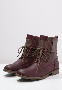 Botas de tobillo de cuero burdeos con puntera redonda, cordones al frente, cremallera lateral, acabado texturizado y detalles en marrón en la suela y el hardware.