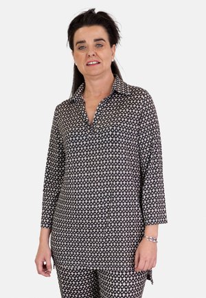 Camisa de patrón en blanco y negro con cuello, mangas tres cuartos y un corte holgado, hecha de una tela suave.
