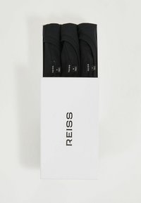  tricouri negre din bumbac, trei rulate, așezate într-o cutie rectangulară albă. Etichetele sunt vizibile, având numele brandului "REISS" scris cu font bold negru.