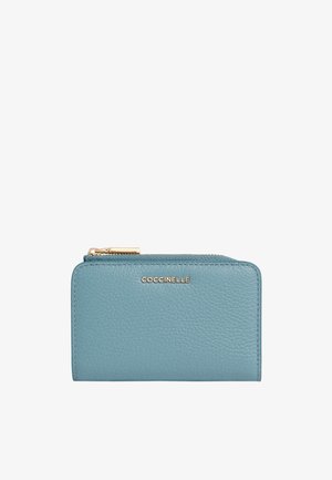 Klein rechthoekig teal leren portemonnee met gouden rits en "COCCINELLE" logo in het midden van de voorkant.