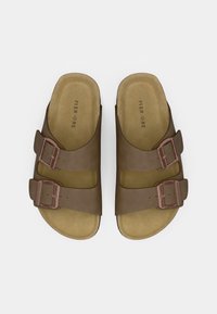 Bruna sandaletter med öppen tå och två justerbara spännen samt vadderade innersulor, märkta "PIER ONE," visade uppifrån mot vit bakgrund.