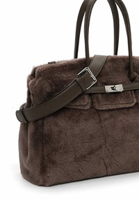 Brun faux fur taske med to læderhåndtag, en aftagelig rem og metalhardwaredetaljer foran. Struktureret, tekstureret form.
