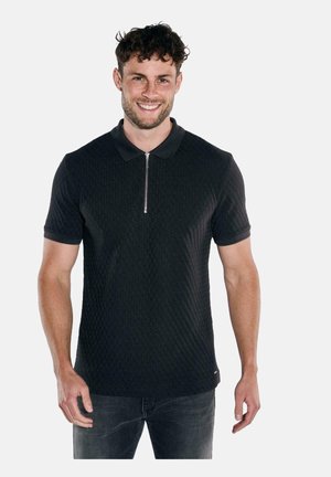 Schwarzes Polohemd mit einem strukturierten Muster, kurzen Ärmeln und einem Reißverschlusskragen. Getragen mit dunklen Jeans, die eine enganliegende Silhouette aufweisen.