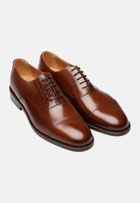 Scarpe da dress in pelle marrone con una texture liscia, caratterizzate da una punta arrotondata, sei passanti e dettagli di cucitura sottili sui lati.