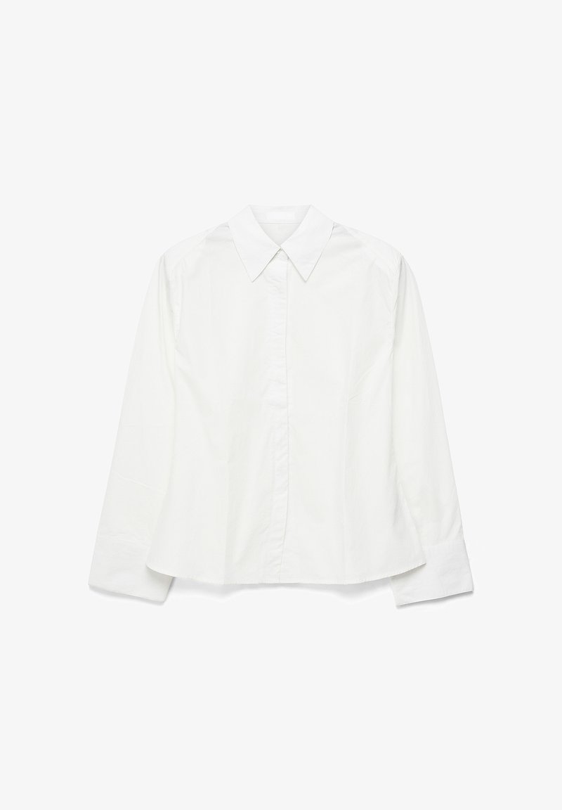 Chemise blanche à manches longues avec col pointu et boutons avant dissimulés, posée à plat sur un fond blanc.