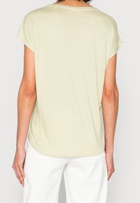 Haut vert clair à manches courtes avec une coupe décontractée, un col arrondi et une texture lisse ; des fentes latérales à l'ourlet offrent un confort supplémentaire.