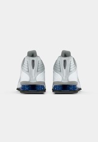 Pair of white and gray athletic shoes with blue cushioning on the sole, viewed from the back against a plain white background.