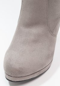 Gray suede ankle boot featuring a rounded toe, smooth texture, and subtle stitching along the side seam, with a flat black sole.