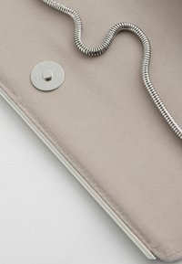 Szara torba z materiału z metalowym zapięciem na zatrzask i srebrnym łańcuszkiem; gładka tekstura, staranne szwy i minimalistyczny design.