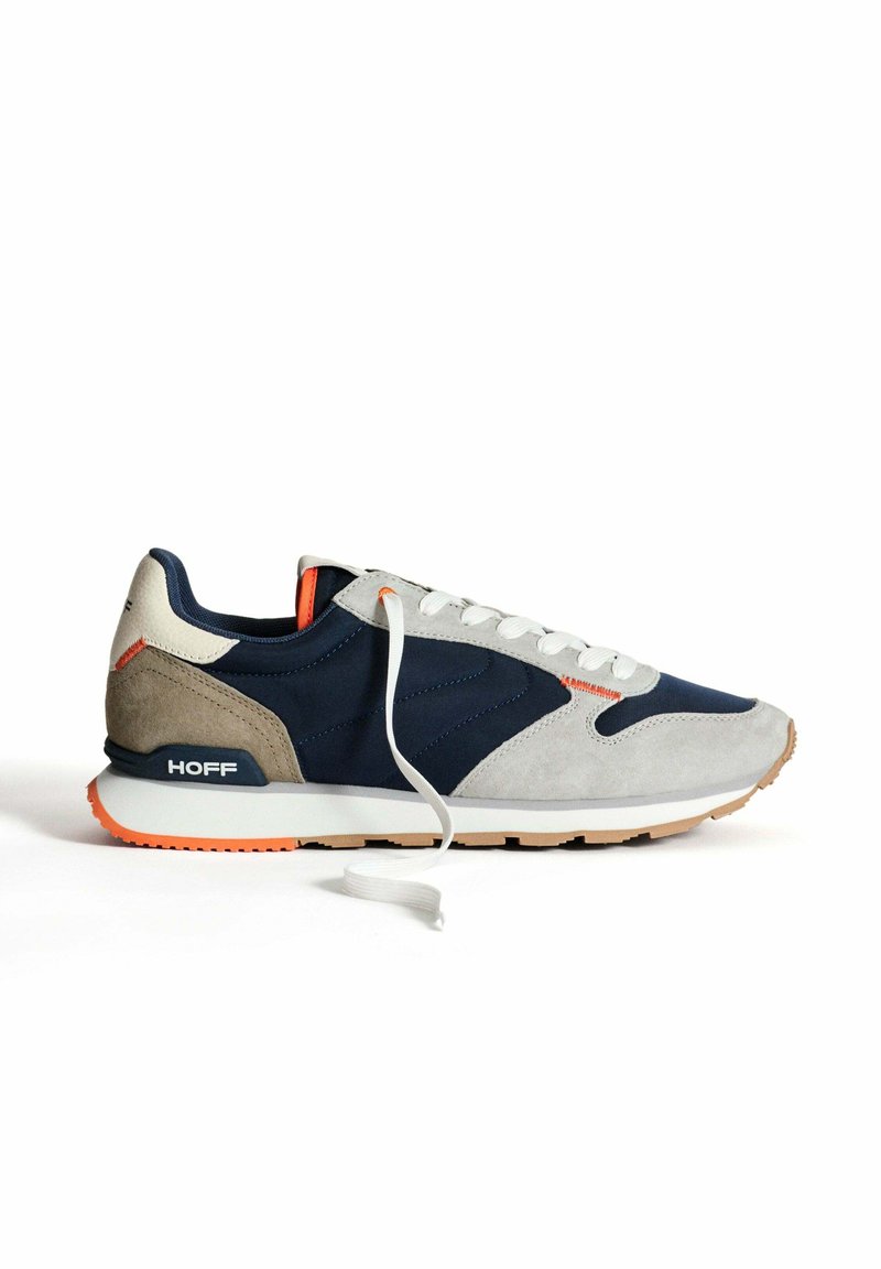 Scarpa con una tomaia blu navy e grigia, realizzata in materiali scamosciati e in rete, con lacci bianchi, dettagli arancioni e una suola in gomma beige.