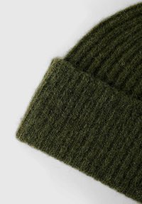 Bonnet en tricot vert avec un design à côtes. Fabriqué en laine moelleuse, il présente un revers plié et une surface texturée.