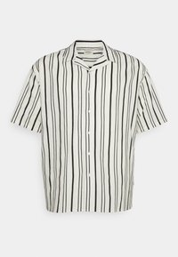 Lyhythihainen nappipusero valkoisena, jossa mustia pystyraitoja, varustettuna leirikauluksella ja pyöristetyillä helmilla. Pehmeä kangas.