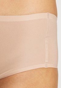 Beige seamless hipster briefs made of soft, smooth fabric with an elasticated waistband and no visible seams for a streamlined fit.