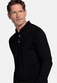Zwarte lange mouwen polo shirt van textuurstof, met een kraag en een knoopsluiting met drie knopen. Klassiek ontwerp met een getailleerde pasvorm.