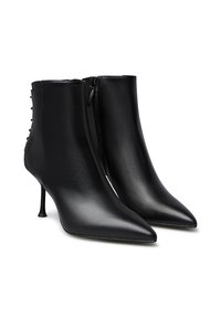 Stivali ankle in pelle nera con punta affusolata, tacco a stiletto sottile, zip frontale e dettaglio decorativo con lacci sul retro.