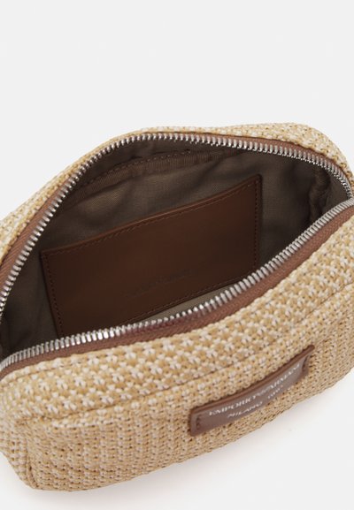 Gewebte Kosmetiktasche aus Stroh in Beige mit einem glatten braunen Stofffutter. Verfügt über einen Reißverschluss und ein Innenfach. Sichtbares Markenakzent aus Leder.