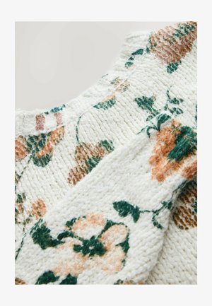 Belo pleteno blago z rožnatimi vzorci v zelenih, rjavih in breskvini tonih, ki prikazuje tkan teksturo in šive v bližnjem posnetku.