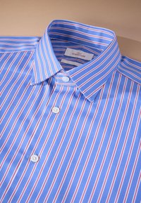 Plava i bijela prugasta košulja s crvenim detaljima, s ovratnikom i bijelim gumbima. Tkanina izgleda glatko s sjajnim teksturom.