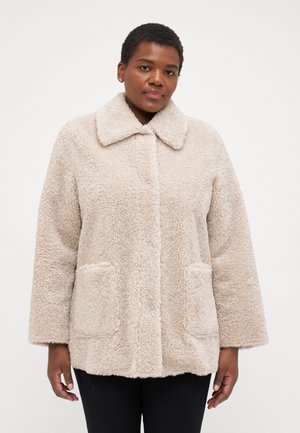 Beige, fluffy outerwear jacket with a collar, two front pockets, and a relaxed fit. Soft texture, visible stitching, and cozy appearance.