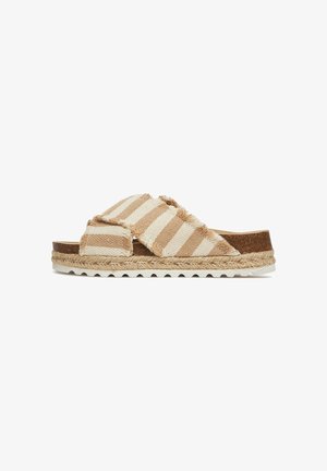 Sandalias de tela tejida con diseño a rayas beige y blanco. Presentan bordes deshilachados, plantilla de corcho y media suela de yute trenzado con suela de goma blanca.