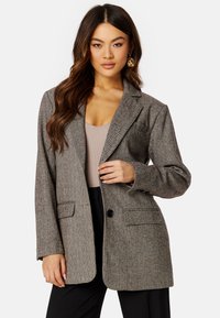 Blazer a motivo pied de poule grigio con dettagli a revers, due tasche frontali, chiusura a un bottone e vestibilità rilassata. Tessuto testurizzato con un motivo sottile.