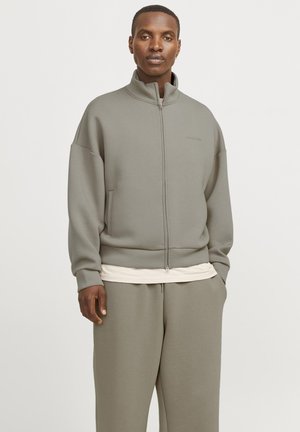 Grå zip-up sweatshirt med høj krave, løs pasform og ribbede manchetter. Sammen med matchende grå bukser med en blød stofstruktur.