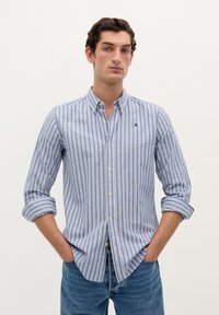Kølig button-up skjorte i bomuld med blå og hvide lodrette striber, spread collar og optrukne ærmer. Lille logo over brystlommen.