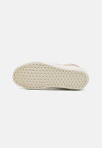 Sneakersålen har en teksturert, kremfarget gummiyttersåle med et diamantmønster for grep og en lett hevet kant.