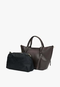 Bruine leren tote bag met een getextureerd oppervlak, voorzien van twee handvatten. Ernaast ligt een klein zwart stoffen zakje met een gouden rits.