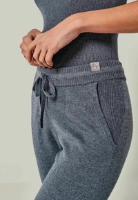 Graue Strick-Sweatpants mit einem gerippten Bund, verstellbarem Kordelzug und Seitentaschen. Auf dem Bund befindet sich ein Stoffetikett.