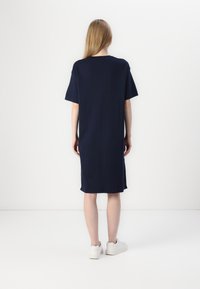 Navy blue T-shirt dress with short sleeves, relaxed fit, knee-length, made from soft fabric, paired with white sneakers.