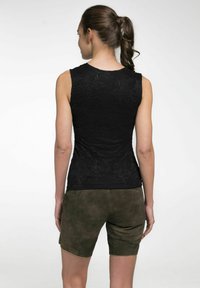 Zwarte mouwloze top met een gestructureerd kantontwerp, gecombineerd met olijfgroene leren shorts. De shorts hebben een nette afwerking en subtiele details.