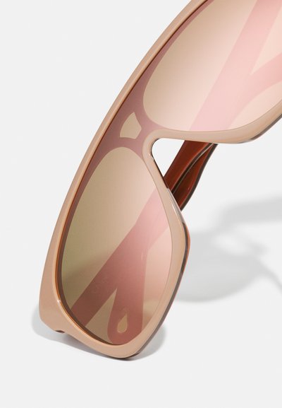 Lunettes de soleil surdimensionnées teintées de rose avec une monture en plastique transparent lisse. Dotées de bords angulaires et de verres dégradés pour un look moderne.