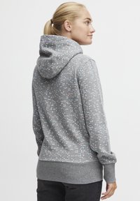 Sudadera gris con patrones circulares multicolores, con capucha ajustable, puños y cintura acanalados. Textura de tejido suave.