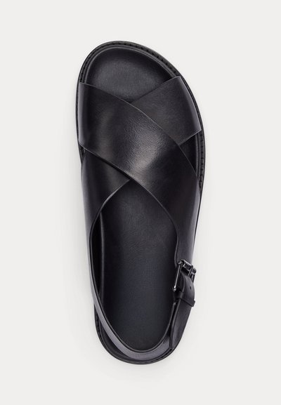 Fekete bőrszandál keresztpántokkal és állítható oldalsó csattal, felülről fehér háttéren nézve.