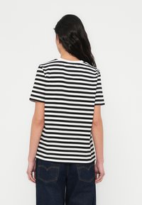 Melns un balts svītrainu īsām piedurknēm T-krekls ar apaļu kakla izgriezumu, izgatavots no mīkstas auduma, ar regulāru piegriezumu un taisnu apakšu.