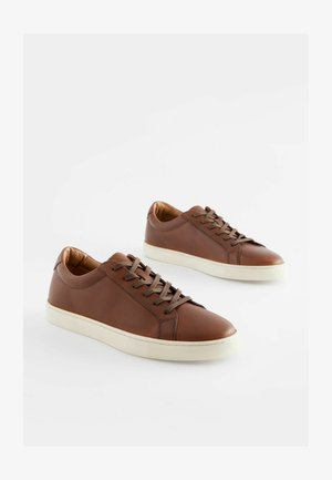 Ruske nahkakevadelise disainiga tennised sileda tekstuuriga, valged kummist tallad ja sobivad pruuni värvi paelad. Ümar nina disain minimaalsete õmblusdetailidega.