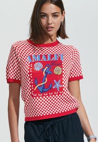 Suéter de punto de manga corta a cuadros rojos y blancos que presenta un diseño bordado de "Amalfi" con conchas y un gráfico de ancla.
