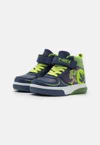 Adidași înalți de culoare bleumarin și verde aprins. Caracteristici: grafică cu dinozaur, bandă Velcro, material cu model și talpă din cauciuc texturat.