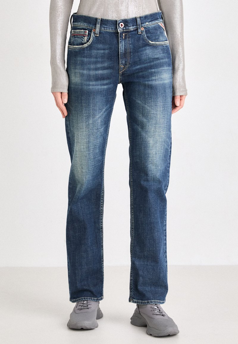Jeans de mezclilla azul para hombre con un acabado desteñido, corte recto, bolsillos frontales con acentos de costura y cierre de botón.