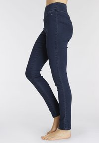 Dunkelblaue Skinny Jeans aus Denim mit hoher Taille, glatter Textur und minimalen Nähdetails. Endet am Knöchel.