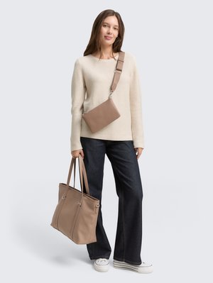 Un pull en maille beige, un pantalon en denim foncé évasé, des baskets blanches, un grand sac fourre-tout beige et un petit sac crossbody avec une sangle.