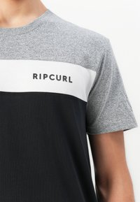 Kortærmet T-shirt med grå top og ærmer, hvid bryststribe, sort nederste del og "RIPCURL" logo på den hvide stribe.